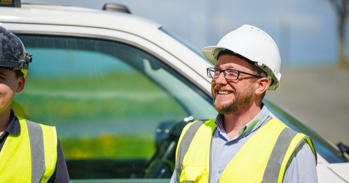 Two operatives in high vis vests standing in front of white van