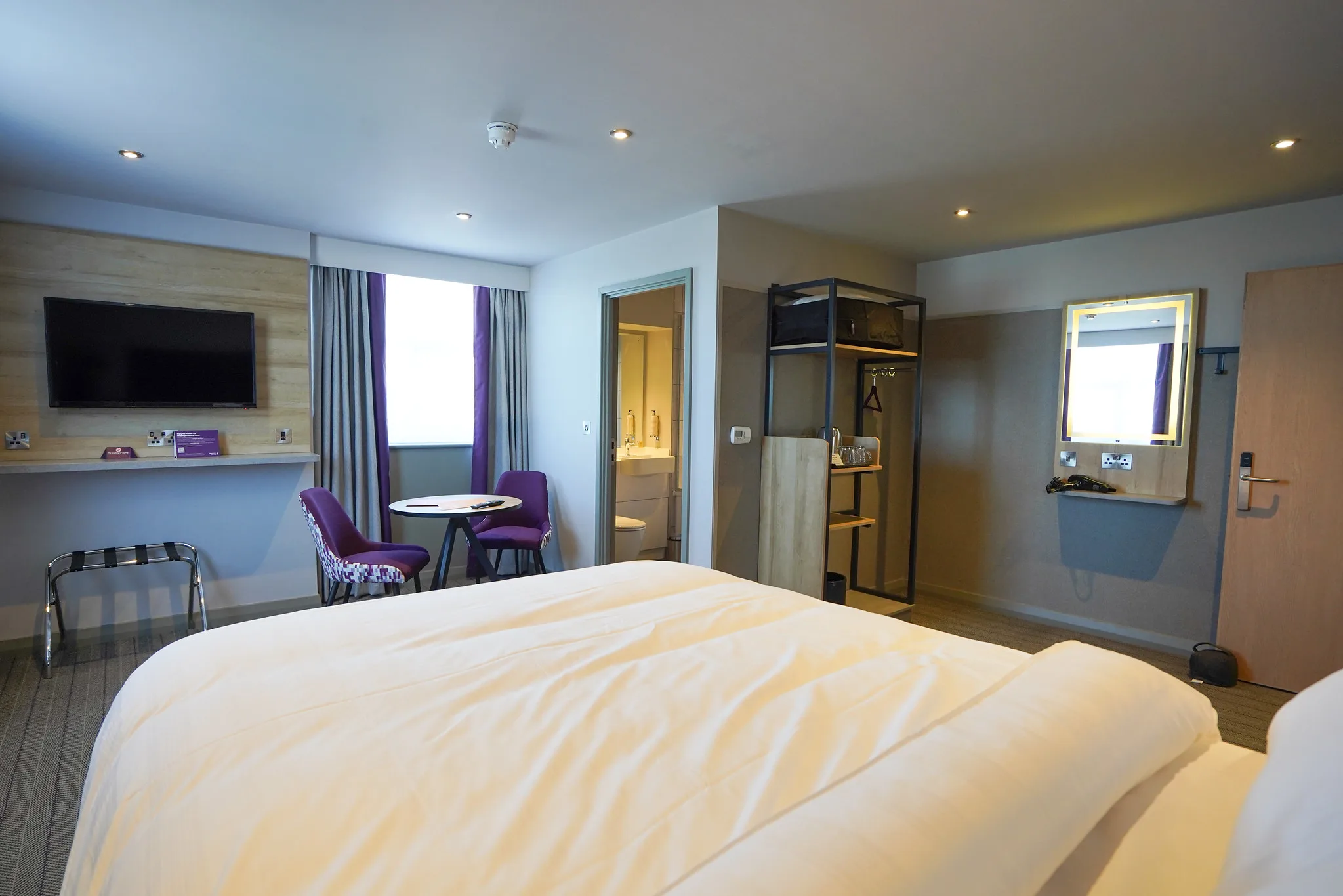 premier inn hotel room with bed tv dinning table open wardrobe mirror entrance to ensuite